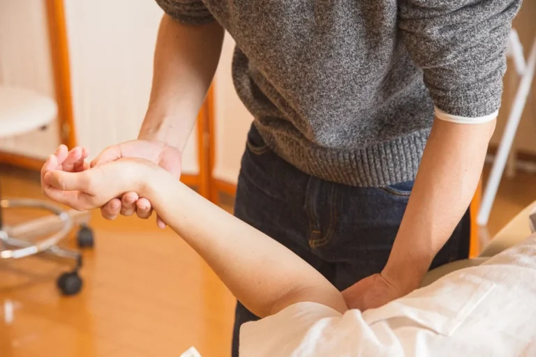 hands of a male therapist treating a female client's arm during craniosacral therapy session
