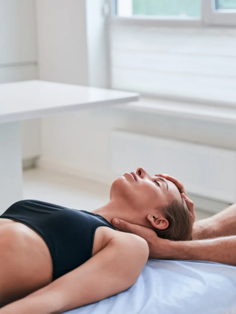 young female patient lying on a massage table as the therapist is performing an evaluation of her neck