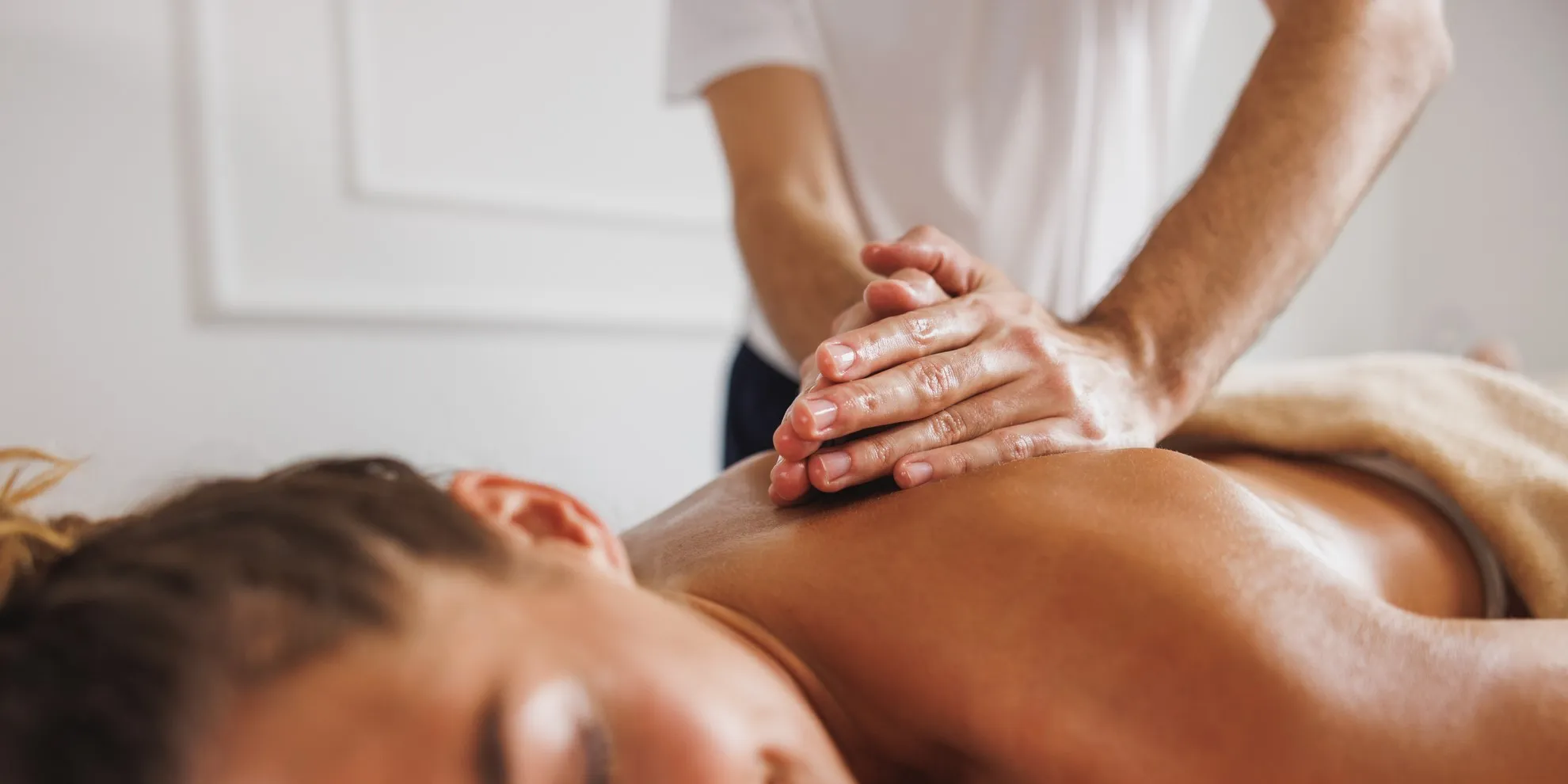 νεαρή γυναίκα λαμβάνει μασάζ πλάτης από έναν θεραπευτή